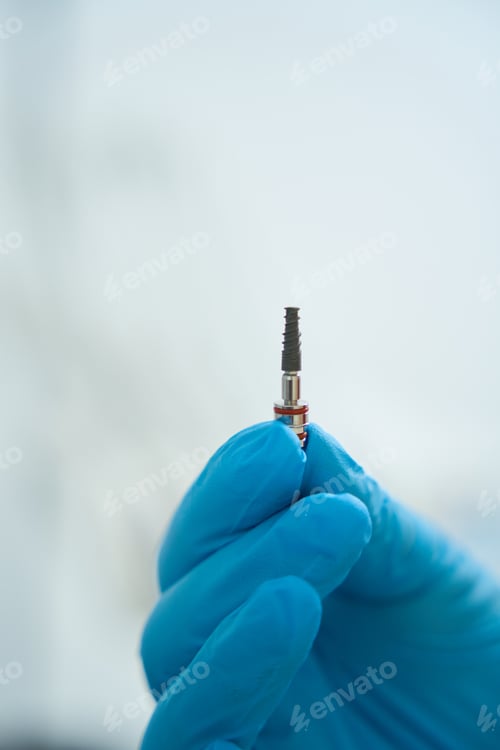 Preview: Dentist hand in medical gloves holds pin for tooth restoration