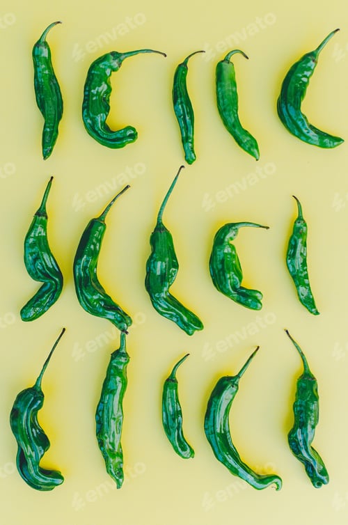 Preview: Minimal flat lay of colorful green shishito peppers on a yellow background