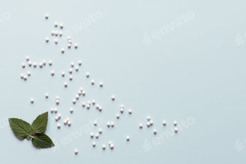 Preview: Homeopathic globules and mint leaves on blue background. Alternative medicine herbs