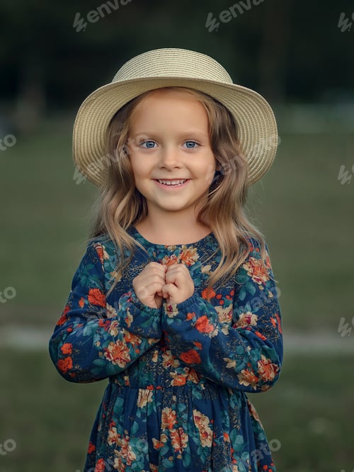 Preview: close-up portrait of a little caucasian girl in a dress and hat in nature