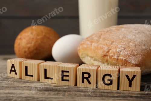 Preview: Food allergy. Bread, egg, milk and cubes on wooden table, closeup