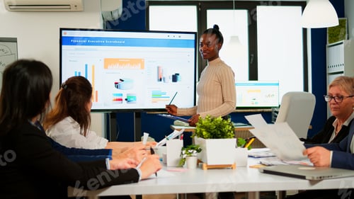 Preview: Black woman worker explaning company statistics in front of colleagues