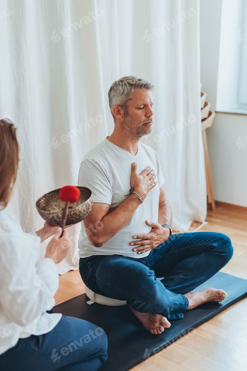 Preview: A man meditating with a sound bowl, and woman holds it during a calming sound therapy session