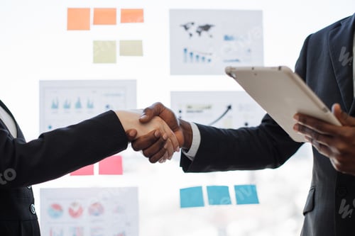Preview: Man with tablet shaking hands with woman in meeting room