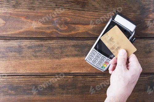 Preview: Close up of man hand holding bank card near payment terminal, Paypass technology concept
