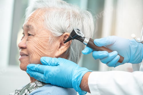 Preview: Audiologist or ENT doctor use otoscope checking ear of asian senior woman patient.