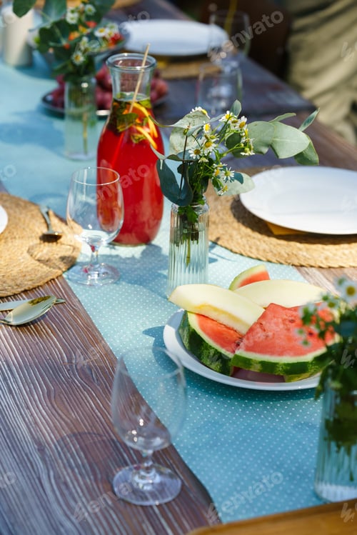 Preview: Close upof a set table at a summer garden party. Table setting with glasses, lemonade, fresh fruits