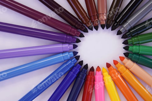 Preview: Colorful markers set up in a circle with their tips pointing to a round copy space in the middle