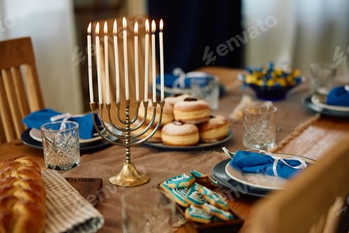 Preview: Lit menorah and table setting prepared for celebration of Jewish Festival of lights.