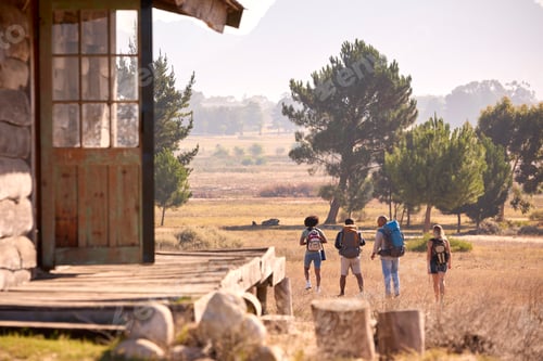 Preview: Rear View Of Group Of Friends With Backpacks Hiking In Countryside Together