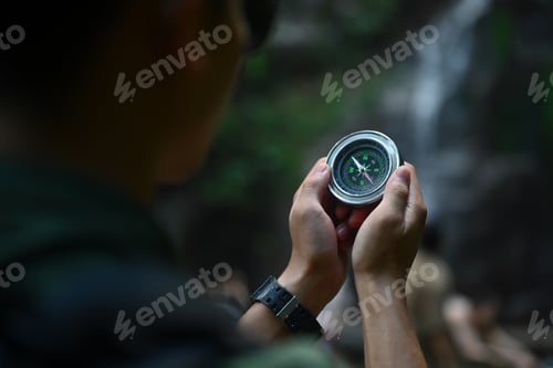 Preview: Close up view of male hiker using compass for directions while exploring nature in the forest