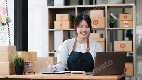 Preview: A portrait of a young Asian woman, e-commerce employee sitting in the office full of packages in the