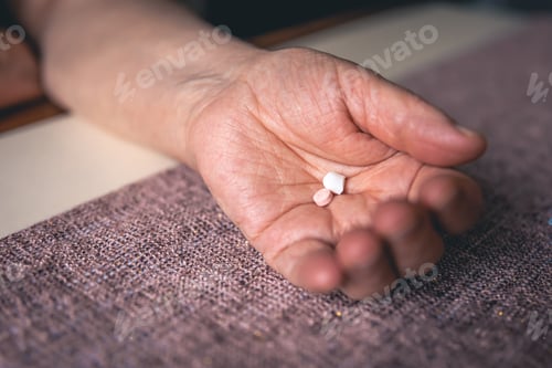 Preview: Pills in the hands of an old woman, close-up.