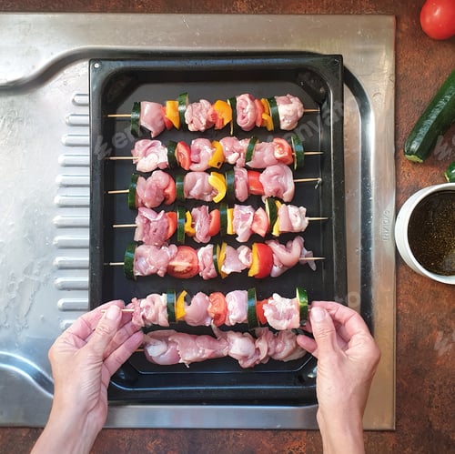 Preview: overhead view of person preparing skewers with chicken and vegetables ready for barbecue