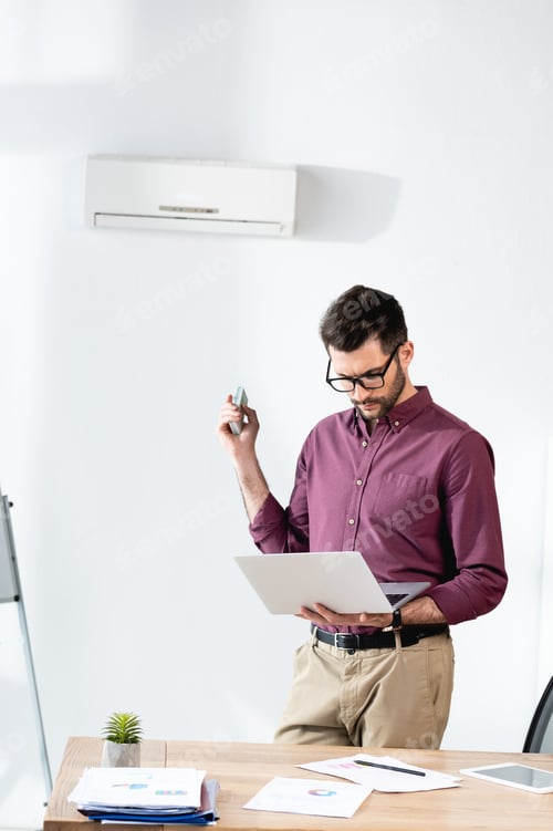 Preview: Man Holding Laptop and Phone in Office
