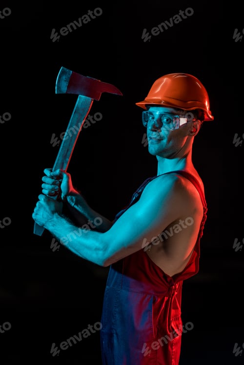 Preview: shirtless fireman in overall, hardhat and protective goggles holding flat head axes isolated on