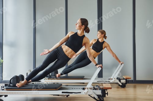Preview: Two women in sportive wear and with slim bodies have fitness yoga day indoors together