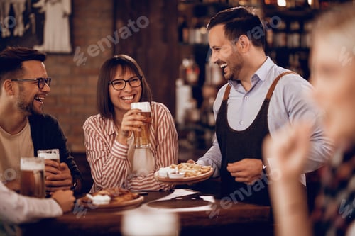 Preview: Happy waiter having fun with customers while serving them in a pub.