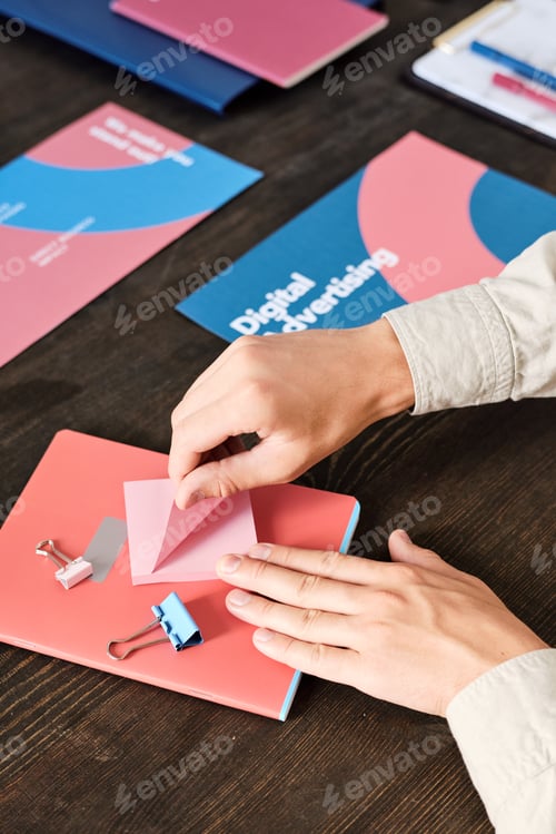 Preview: Hands of office manager sitting by table and unsticking notepaper to make notes