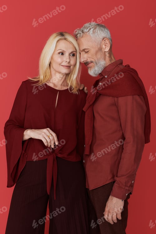 Preview: Lovely senior couple share a tender moment in stylish outfits against a vibrant backdrop