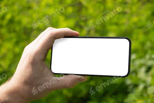 Preview: Man holding blank smartphone with nature green background