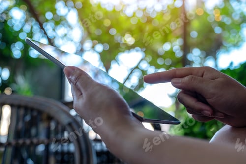 Preview: Closeup image of hands holding and pointing at a black tablet pc screen with blur green background