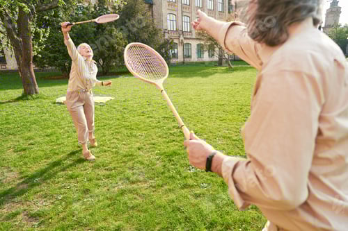 Preview: Happy senior couple playing badminton in the park