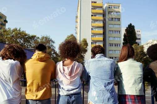Preview: Rear view of friends standing against railing in city