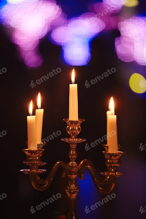 Preview: Burning candles on bronze candlestick against dark background at home.candles in the interior.