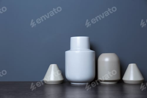 Preview: Beautiful ceramic vases on table against color wall with space for text