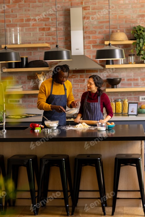Preview: Happy diverse couple baking christmas cookies preparing dough in kitchen, copy space