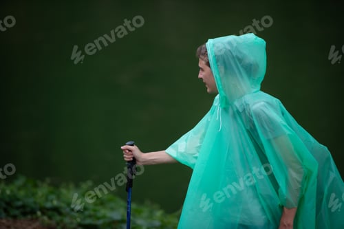 Preview: Girl in raincoat with walking stick on the background of the lake