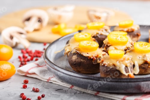 Preview: stuffed fried champignons with cheese, kumquats and green peas on a gray concrete