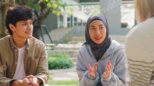 Preview: Small Asian group of people sit in a close circle and talk to a therapist in park.