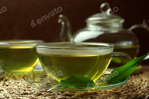 Preview: Fresh green tea in glass cups, leaves and teapot on table, closeup