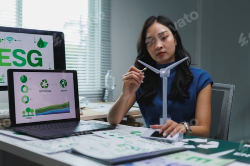 Preview: Businesswoman analyzing esg data and holding wind turbine model