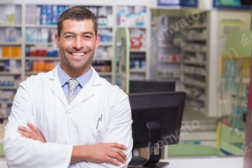Preview: Male pharmacist standing behind pharmacy counter wearing lab coat and smiling at computer monitor