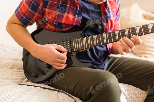 Preview: Young millennial man, guy playing electric guitar. Stay at home, home activity, learning classes