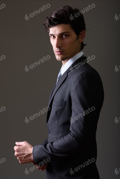 Preview: Studio shot of young handsome businessman fixing sleeve in the d