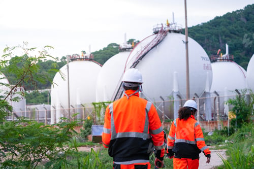 Preview: Two engineers in high-visibility safety gear and hard hats discuss project plans