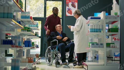 Preview: Social caretaker helping elderly person in wheelchair to come at drugstore