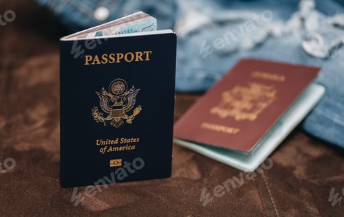 Preview: american passport and Jamaican passport along with blue jeans pants on brown couch