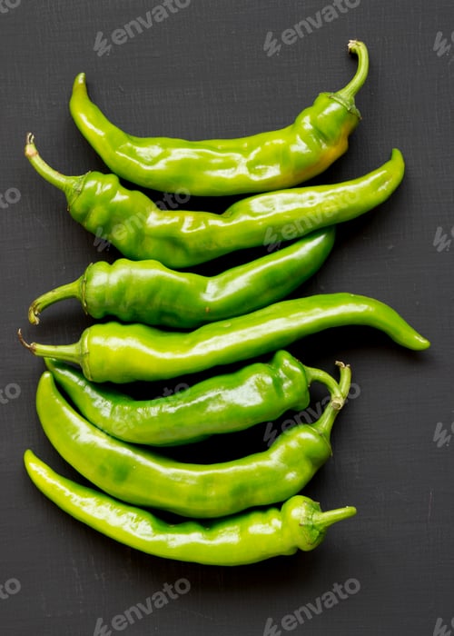 Preview: Green chili peppers on black surface, top view. Flat lay, from above, overhead. Close-up.
