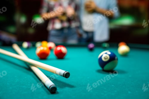 Preview: Portrait of young couple having fun playing billiard together.