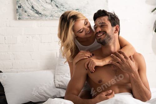 Preview: happy smiling couple hugging in bed in the morning