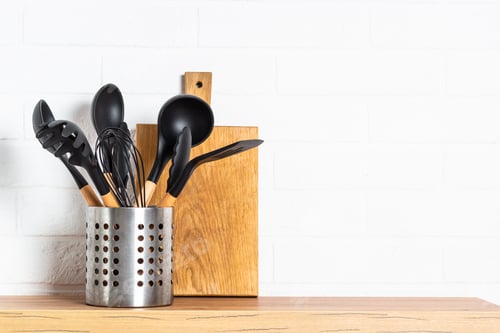 Preview: Cooking tools with wooden cutting boards, oil and shaker at white modern kitchen interior.