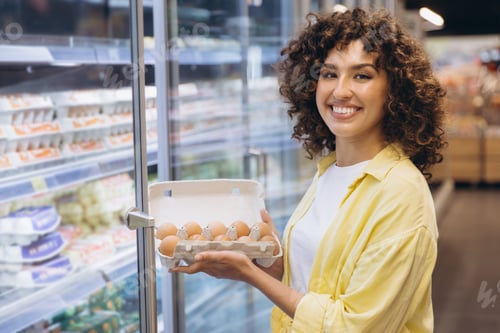 Preview: Young Woman Choosing Eggs in Supermarket Refrigerator