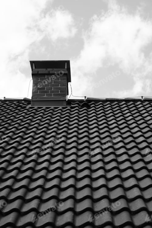 Preview: Grayscale shot of roof tiles and a chimney against a cloudy sky