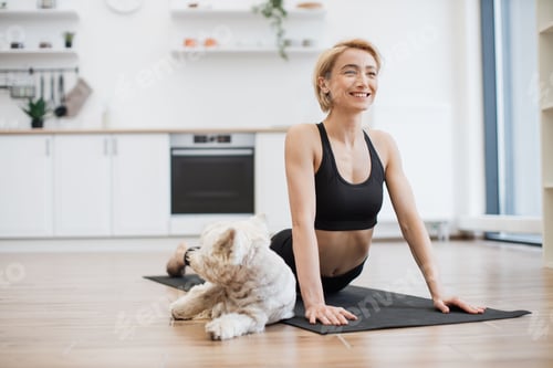 Preview: Female in Cobra Pose stretching with dog on mat at home