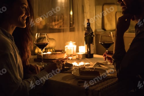 Preview: Couple having a lovely date by the candlelight, drinking red wine and serving dessert.